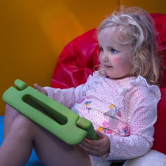 young girl holds ipad in green case