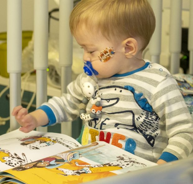 baby with picture book in hospital cot