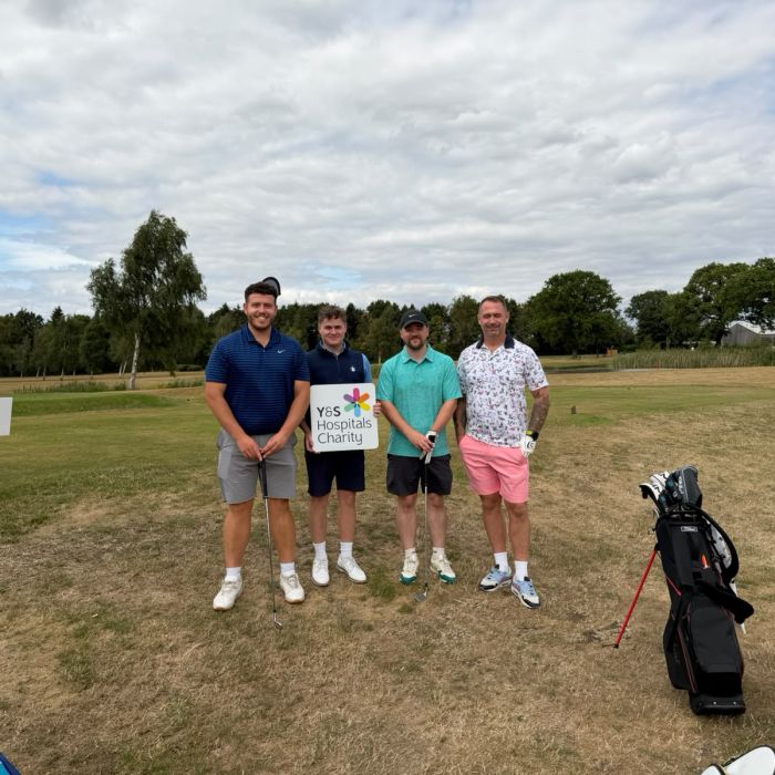four golfers stood with the charity logo sign