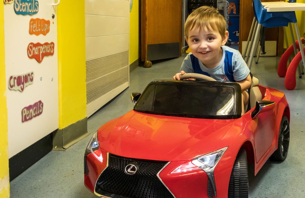 Little boy in a red push along toy racing car