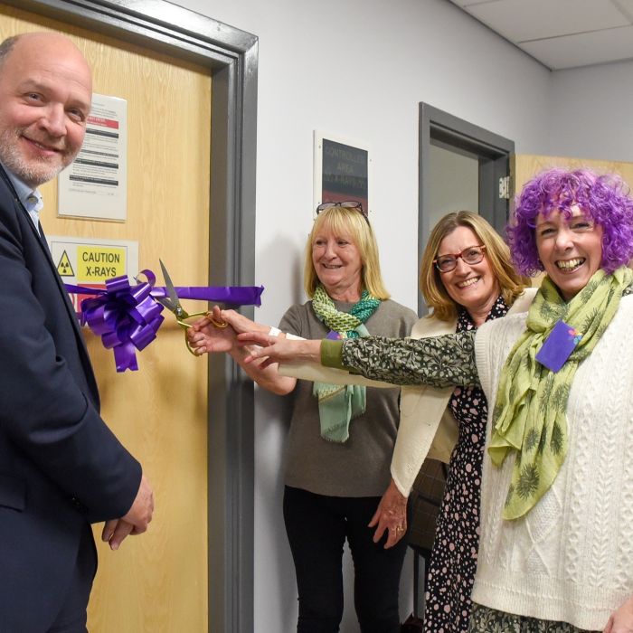 4 individuals cutting a ribbon to formally open the new facility