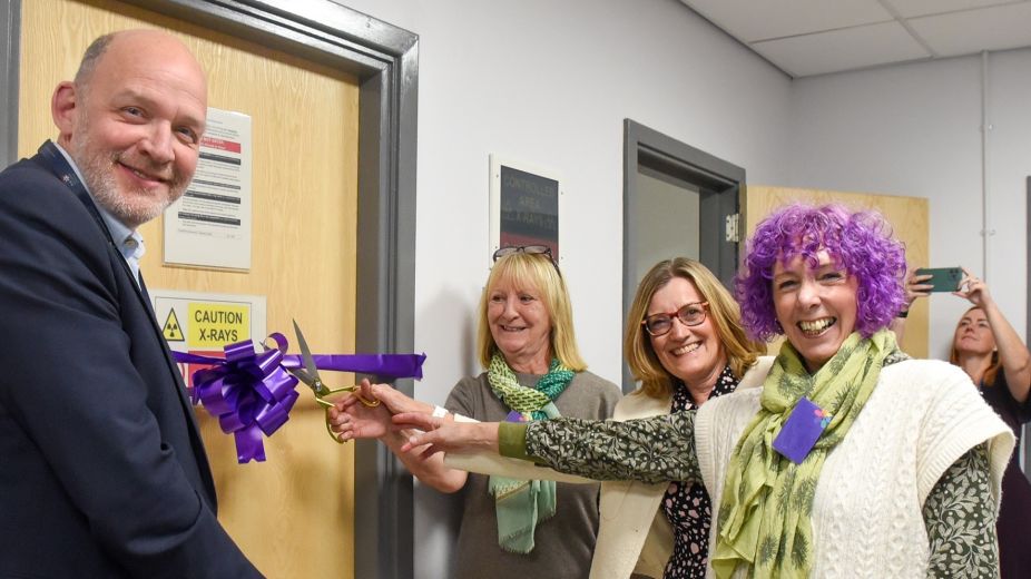 4 individuals cutting a ribbon to formally open the new facility