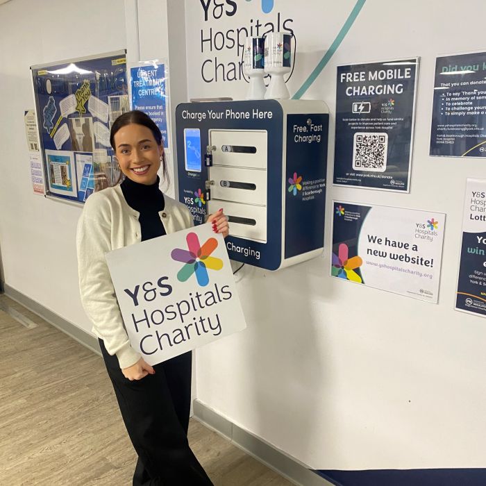 Supporter smiling with charity logo board sign