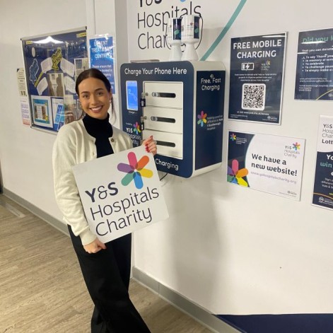 Supporter smiling whilst holding charity logo board