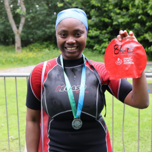 Swimmer holding up swimming hat after completing the great north swim