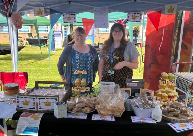 Two supporters smiling by a bake sale stand