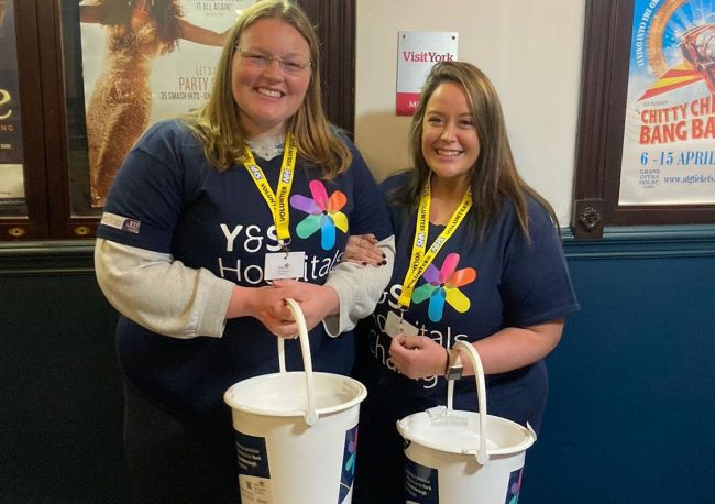 Two supporters smiling holding charity collection buckets